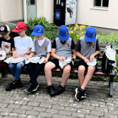 Bērni pie muzeja apsēdušies uz soliņa.